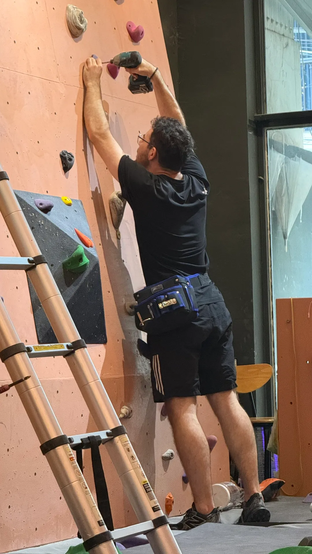 A setter drilling a new hold onto the wall